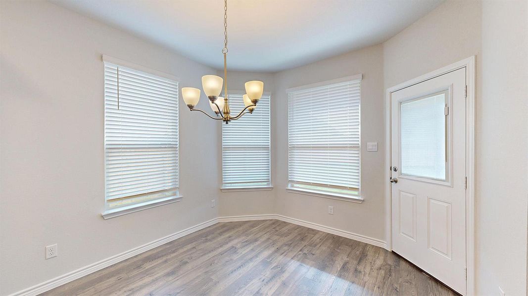 Dining area with wood-look flooring, a chandelier, and a white paneled door with an upper window