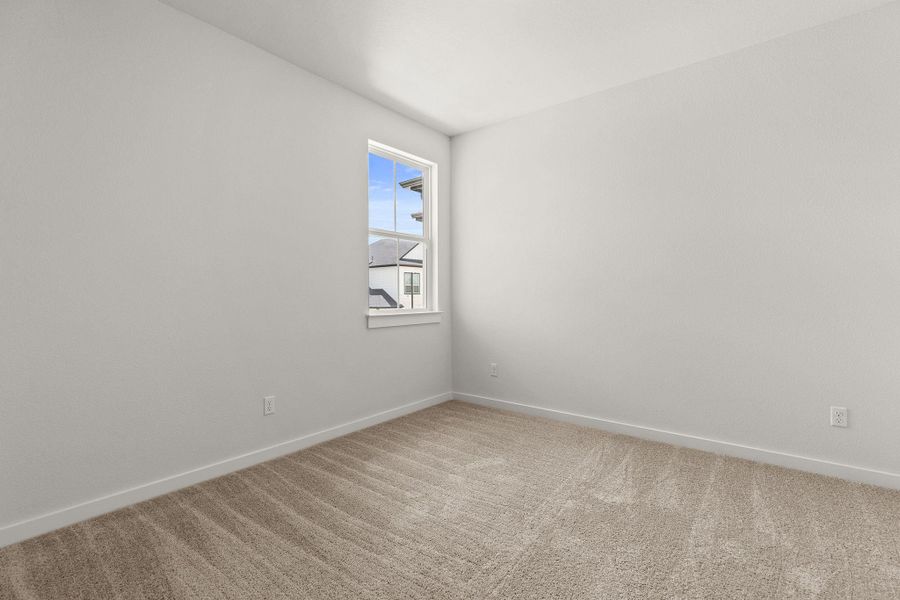 A well-lit bedroom offering a neutral palette and plush carpeting.
