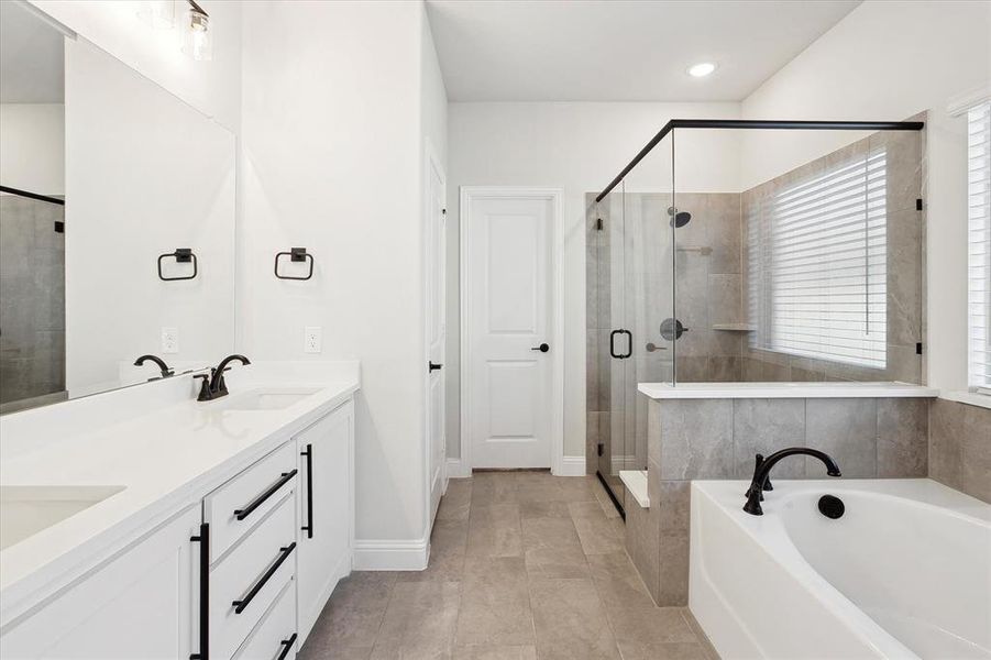 Bathroom featuring double vanity, a garden tub, a stall shower, baseboards, and recessed lighting
