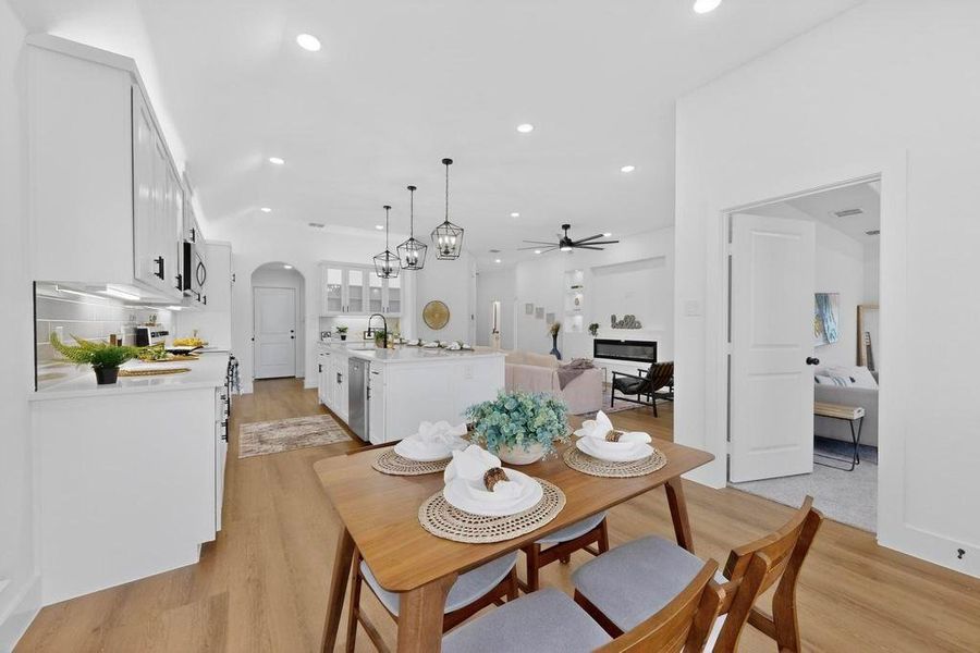 Dining room with arched walkways, light wood finished floors, a ceiling fan, and recessed lighting Dining room with arched walkways, light wood finished floors, a ceiling fan, and recessed lighting