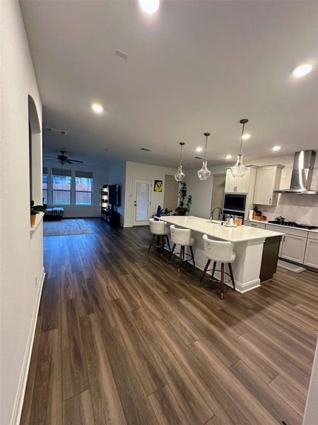 Spacious open-concept living area featuring wood-finish flooring, recessed lighting, and an expansive kitchen island with pendant lighting Spacious open-concept living area featuring wood-finish flooring, recessed lighting, and an expansive kitchen island with pendant lighting