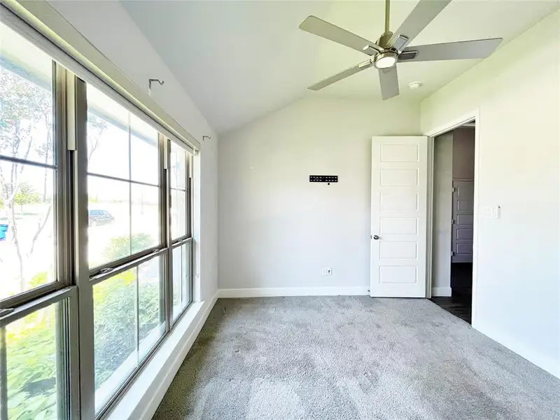 Unfurnished bedroom featuring vaulted ceiling, carpet, and a ceiling fan Unfurnished bedroom featuring vaulted ceiling, carpet, and a ceiling fan
