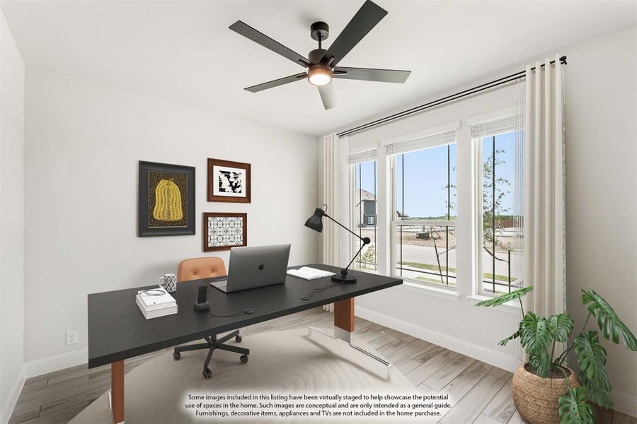 Home office with dark desk, ceiling fan, large windows, and hardwood floors