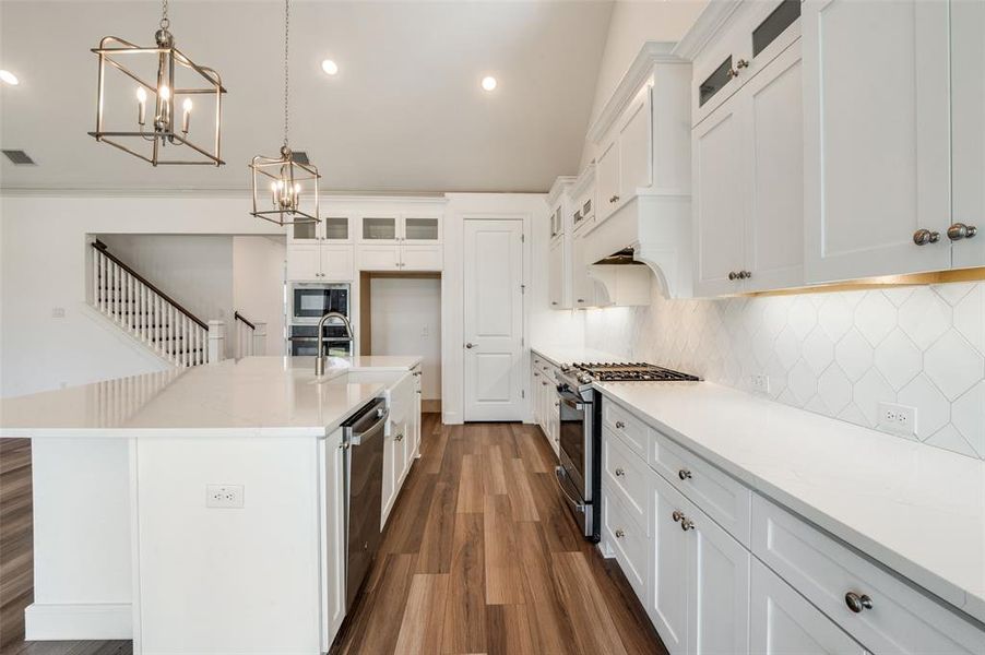 Kitchen featuring a kitchen island with sink, light stone countertops, dark wood-type flooring, appliances with stainless steel finishes, and recessed lighting Kitchen featuring a kitchen island with sink, light stone countertops, dark wood-type flooring, appliances with stainless steel finishes, and recessed lighting