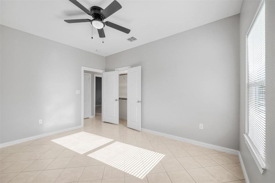 Unfurnished bedroom with ceiling fan and light tile patterned flooring