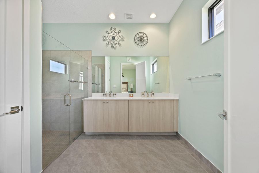 Full bath with plenty of natural light, a stall shower, double vanity, recessed lighting, and light tile patterned floors