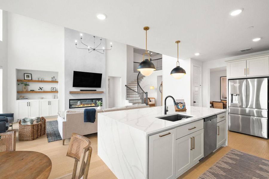 Open-concept living space featuring a gourmet kitchen island with a waterfall quartz countertop, contemporary pendant lighting, and stainless steel appliances Open-concept living space featuring a gourmet kitchen island with a waterfall quartz countertop, contemporary pendant lighting, and stainless steel appliances