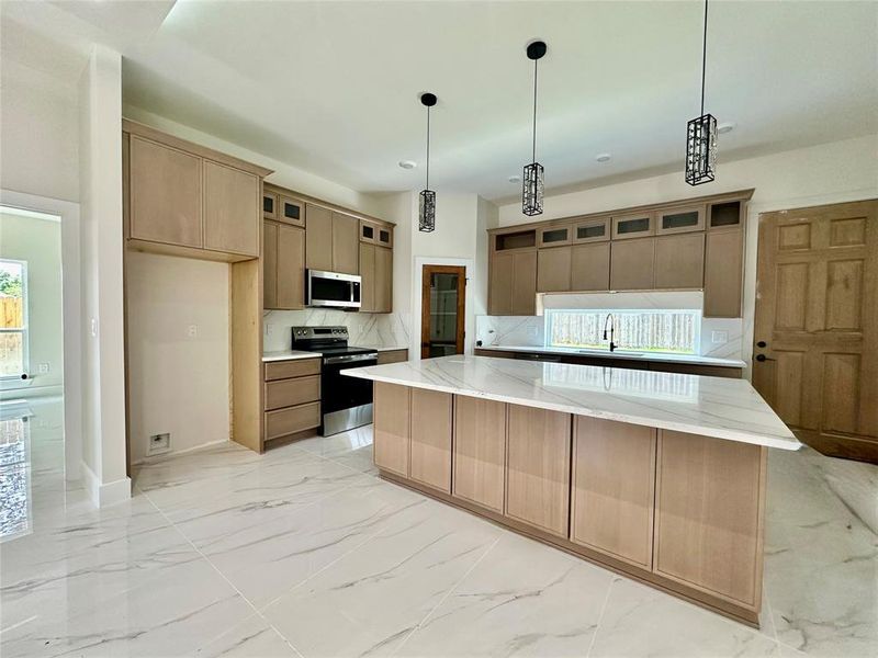 Kitchen featuring stainless steel appliances, a sink, backsplash, light marble finish floors, and glass insert cabinets