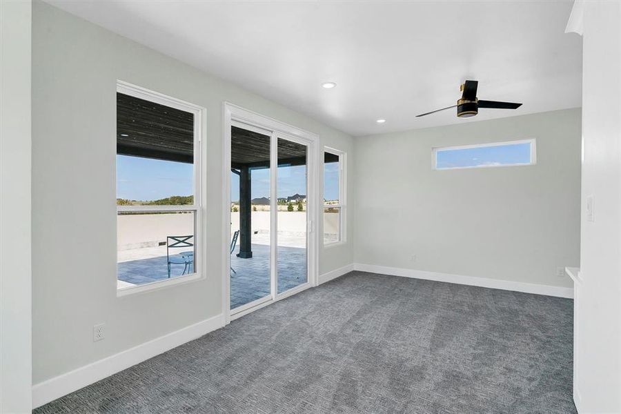 Carpeted spare room featuring ceiling fan and a wealth of natural light