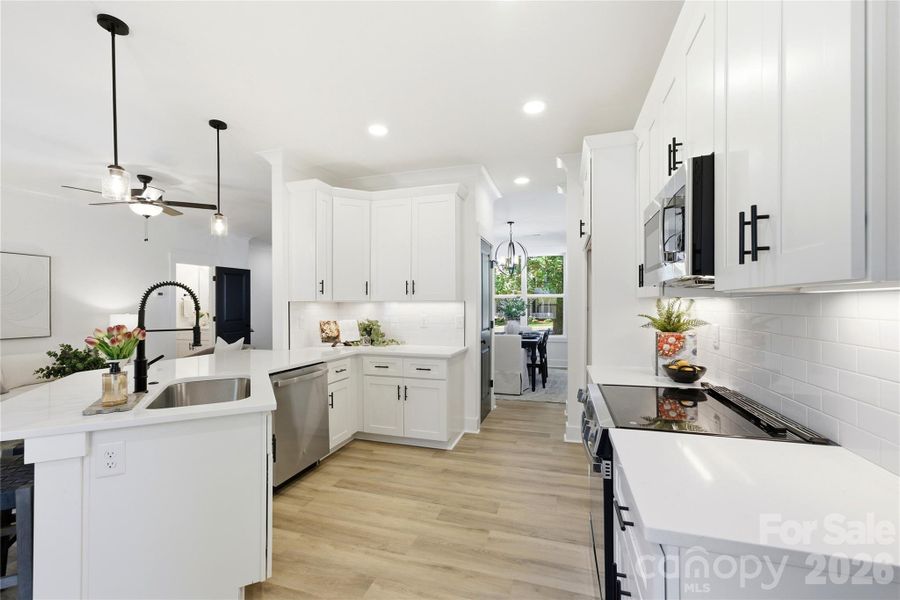 A chef-inspired kitchen featuring white quartz countertops, Shaker cabinetry, and thoughtful storage throughout