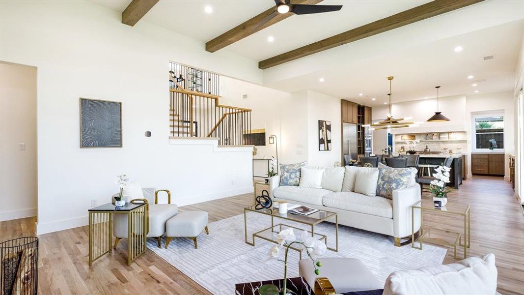 Living room featuring sink, a fireplace, light wood-type flooring, beam ceiling, and ceiling fan