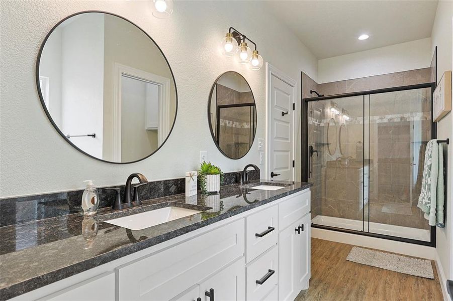Dual vanity with dark stone-finish countertop and white cabinetry Dual vanity with dark stone-finish countertop and white cabinetry