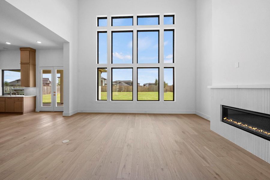 Grand living area featuring dramatic windows, soaring ceilings, and a beautiful fireplace.