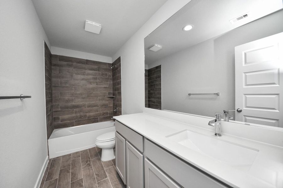 Secondary bath features tile flooring, bath/shower combo with tile surround, light stained wood cabinets, beautiful light countertop. Secondary bath features tile flooring, bath/shower combo with tile surround, light stained wood cabinets, beautiful light countertop.