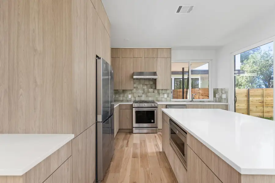Kitchen with modern cabinets, stainless steel appliances, and light brown cabinetry