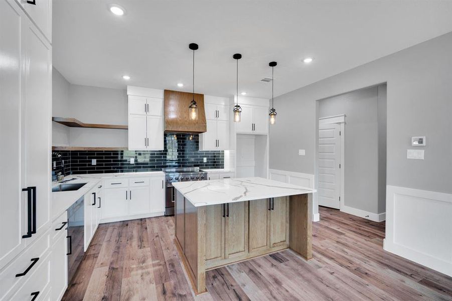 Kitchen with open shelves, light stone counters, tasteful backsplash, stainless steel electric range oven, and a kitchen island
