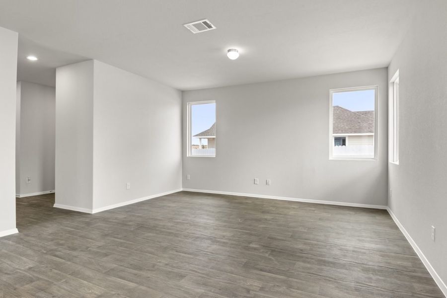 Image of two story home living room with brown flooring and light grey walls and windows Image of two story home living room with brown flooring and light grey walls and windows