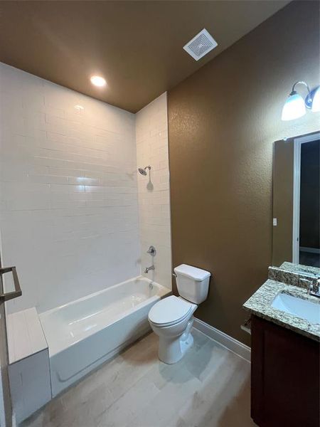 Full bathroom with tiled shower / bath combo, vanity, and toilet