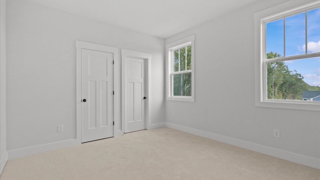 Superior comfort in a secondary bedroom with plush carpet and an oversized walk-in closet
