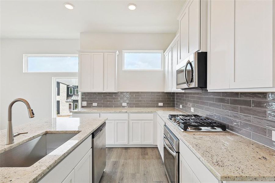 Kitchen featuring stainless steel appliances, backsplash, light hardwood / wood-style flooring, and sink