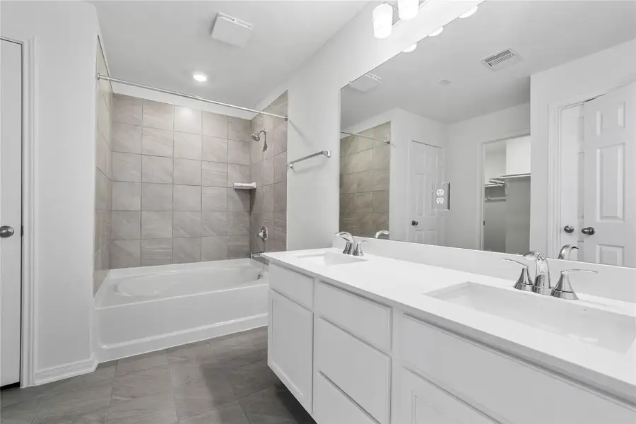 This stunningly updated primary bathroom is truly move-in ready! It features white stained cabinetry with light countertops, dual sinks, a large mirror, a large tub/shower combination with tile surround, walk-in closet with built-in shelving, soaring ceilings, custom paint, and sleek modern finishes throughout. This stunningly updated primary bathroom is truly move-in ready! It features white stained cabinetry with light countertops, dual sinks, a large mirror, a large tub/shower combination with tile surround, walk-in closet with built-in shelving, soaring ceilings, custom paint, and sleek modern finishes throughout.
