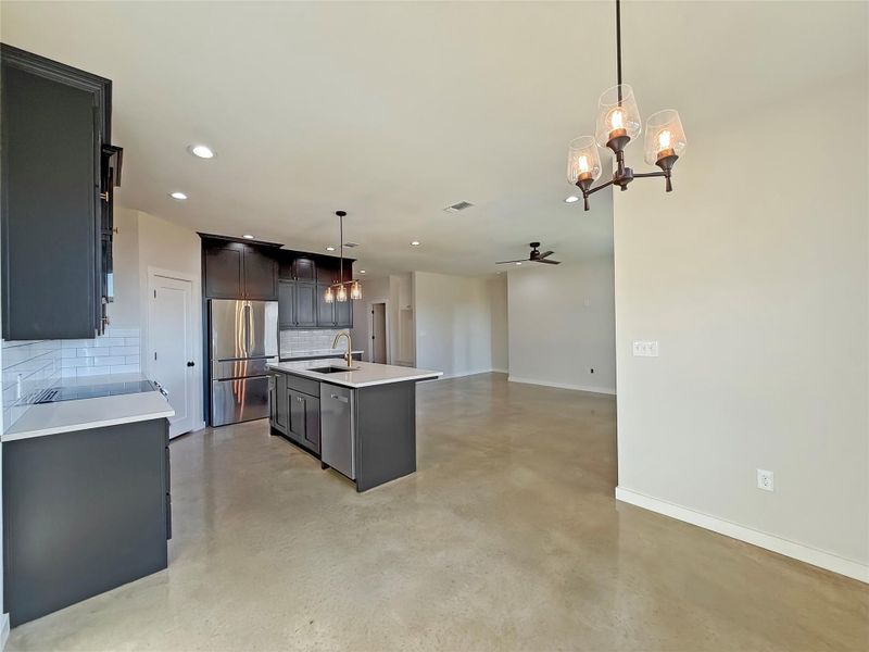 Kitchen featuring a chandelier, a ceiling fan, hanging light fixtures, tasteful backsplash, and appliances with stainless steel finishes