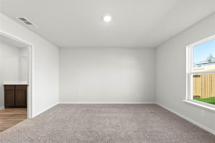 Spare room featuring healthy amount of natural light, light colored carpet, and baseboards