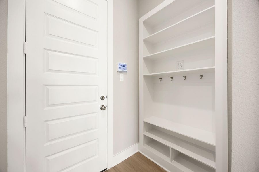 A built-in mudroom keeps everyday life organized with open shelving, storage cubbies, coat hooks, and a convenient drop zone just inside the garage access. A built-in mudroom keeps everyday life organized with open shelving, storage cubbies, coat hooks, and a convenient drop zone just inside the garage access.