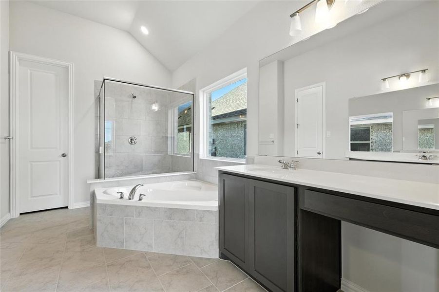 Bathroom with a bath, vanity, tiled shower, and vaulted ceiling Bathroom with a bath, vanity, tiled shower, and vaulted ceiling