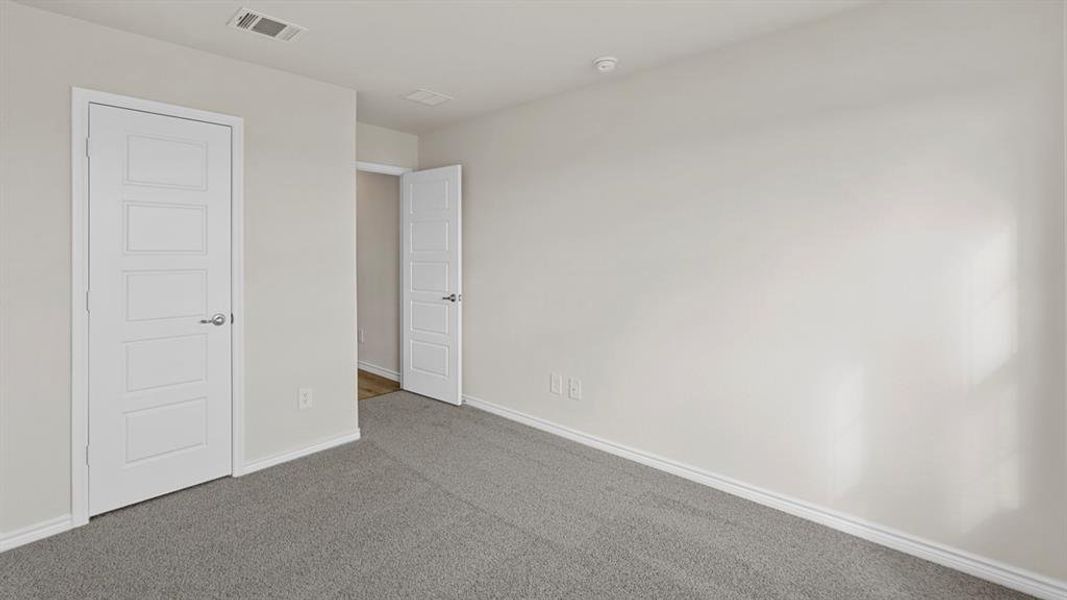 Spacious room featuring neutral grey carpeting and light-toned walls Spacious room featuring neutral grey carpeting and light-toned walls