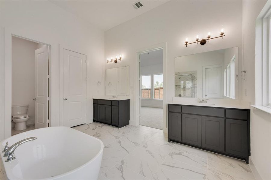 Bathroom with a stall shower, two vanities, a soaking tub, and light marble finish floors Bathroom with a stall shower, two vanities, a soaking tub, and light marble finish floors