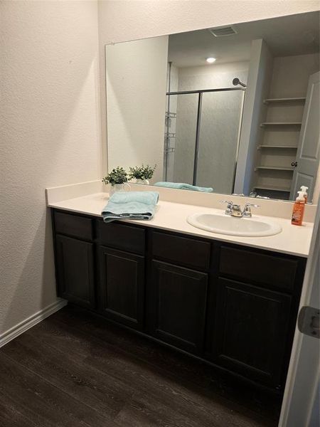 Bathroom with a shower with shower door, vanity, and wood-type flooring