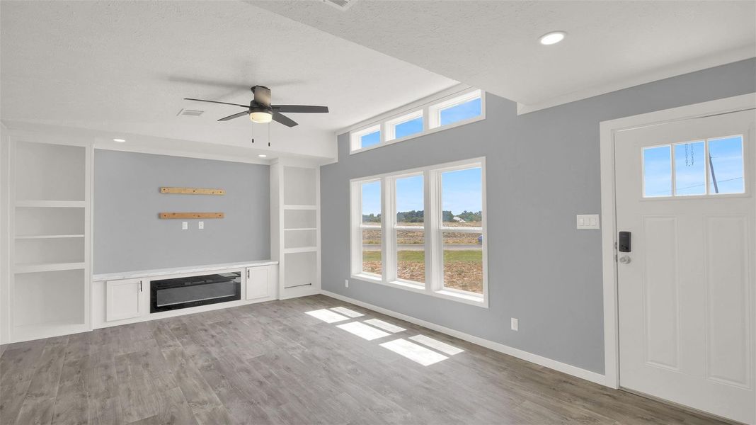 Custom built-ins frame the fireplace in a light-filled living area with wood-look flooring.