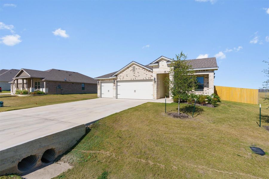 View of front of property featuring driveway, an attached garage, and brick siding