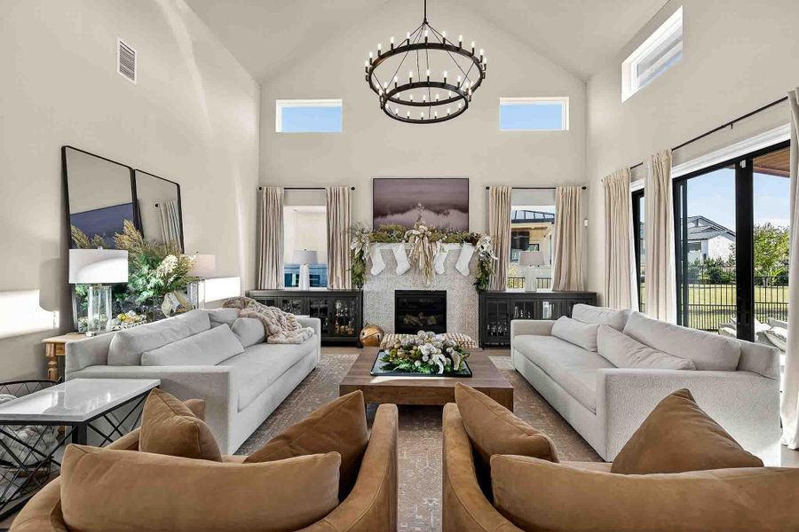 Living area with high vaulted ceiling, a glass covered fireplace, and a chandelier