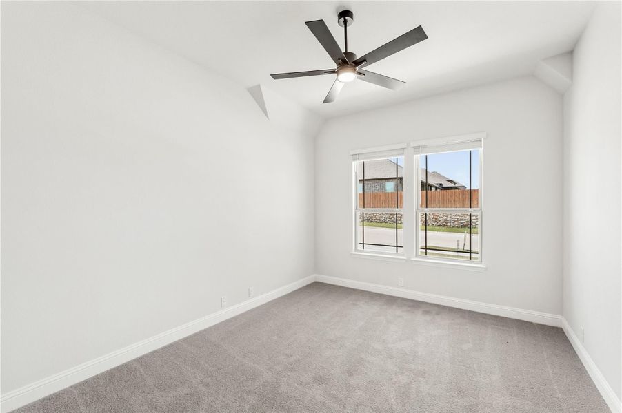 Empty bedroom with vaulted ceiling, ceiling fan, gray carpet, and a double window with backyard view Empty bedroom with vaulted ceiling, ceiling fan, gray carpet, and a double window with backyard view