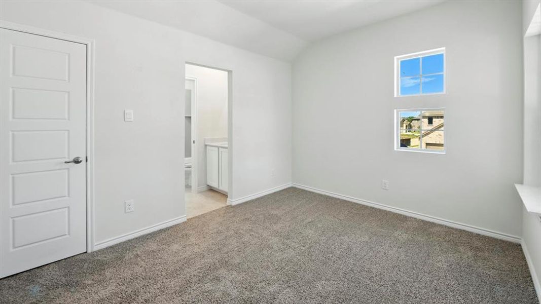 Unfurnished bedroom featuring lofted ceiling, light carpet, and connected bathroom Unfurnished bedroom featuring lofted ceiling, light carpet, and connected bathroom