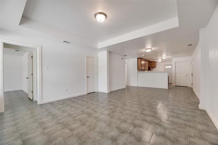 Unfurnished living room with a raised ceiling and light tile patterned floors