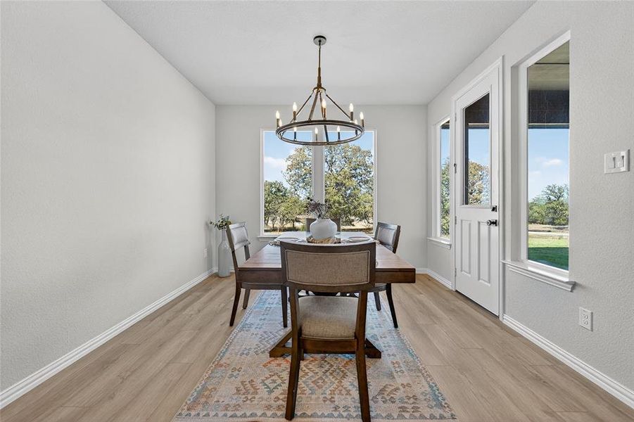 Dining area featuring light wood-style floors, a chandelier, and a textured wall Dining area featuring light wood-style floors, a chandelier, and a textured wall