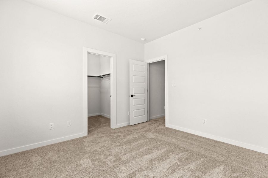 A well-lit bedroom features plush carpeting and two convenient closet entrances.