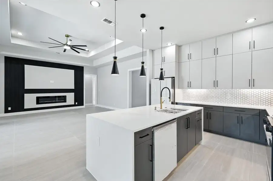 Kitchen featuring a center island with sink, hanging light fixtures, white cabinetry, decorative backsplash, and a tray ceiling Kitchen featuring a center island with sink, hanging light fixtures, white cabinetry, decorative backsplash, and a tray ceiling