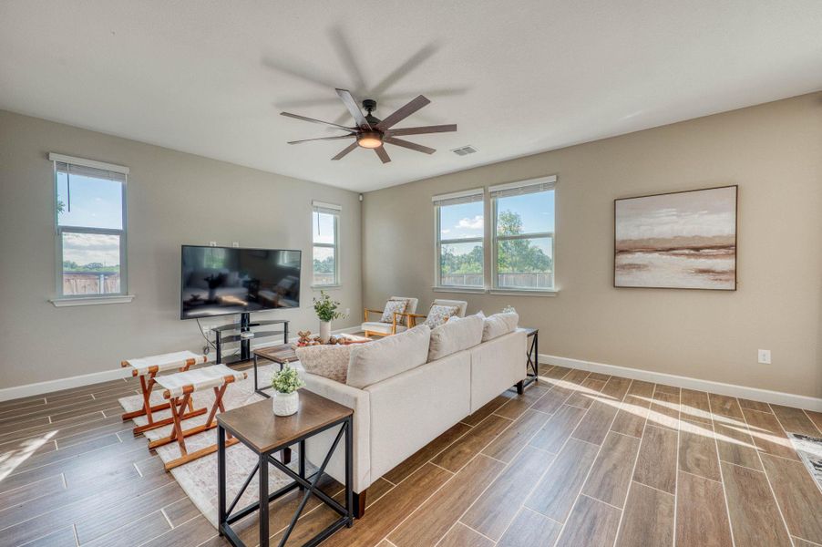 Ample windows invite natural light across the wood-look tile flooring in this open living space. Ample windows invite natural light across the wood-look tile flooring in this open living space.