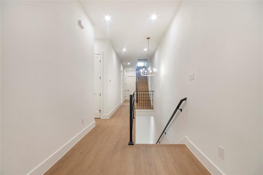 Hall featuring an upstairs landing, light wood finished floors, a chandelier, and recessed lighting