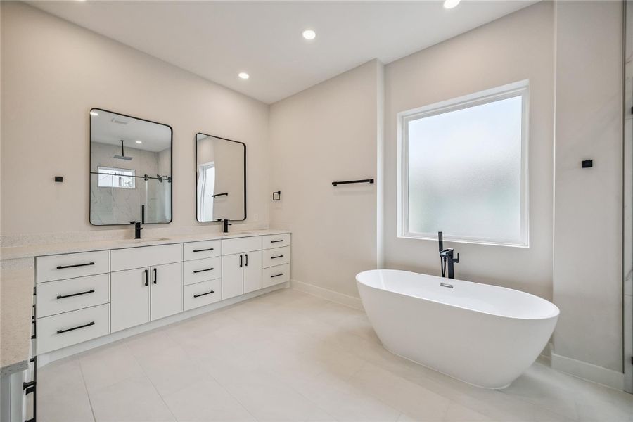 The primary bath was designed with both scale and functionality in mind, featuring dual vanities, a freestanding soaking tub, and generous floor space throughout. Clean lines and soft natural light continue the home’s contemporary finish palette. The primary bath was designed with both scale and functionality in mind, featuring dual vanities, a freestanding soaking tub, and generous floor space throughout. Clean lines and soft natural light continue the home’s contemporary finish palette.