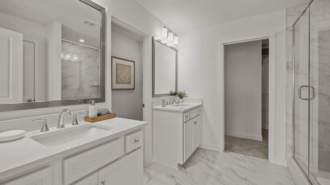 Spa-inspired primary bathroom with separate comfort height vanities and high-end finishes in the Townsend Design by DRB Homes