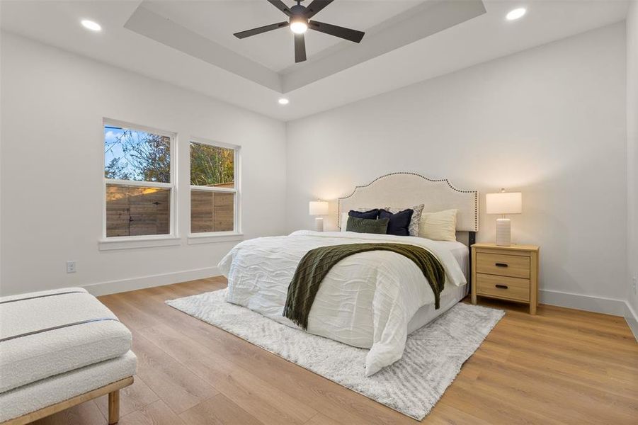 Bedroom featuring a tray ceiling, light wood finished floors, a ceiling fan, and recessed lighting