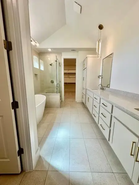 Vast tile flooring leads to a spacious primary bathroom featuring a freestanding tub and walk-in shower.