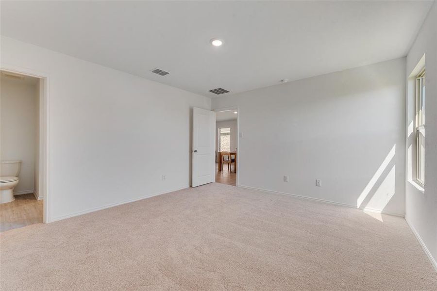 Unfurnished bedroom with connected bathroom and light carpet