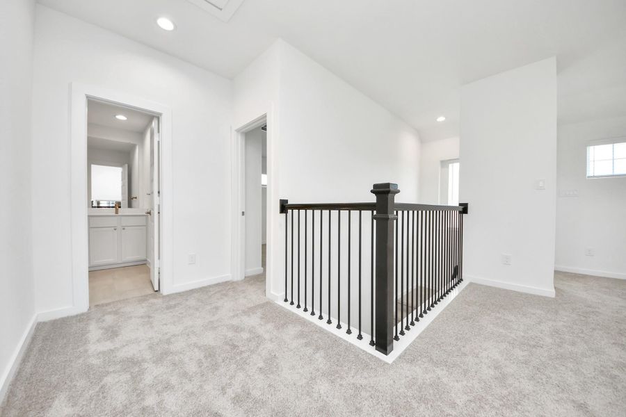 Come upstairs and relish a day of relaxation in this loft area! Ideal as an additional living space or game room, it boasts plush carpeting, high ceilings, custom paint, and windows that flood the area with abundant natural light.