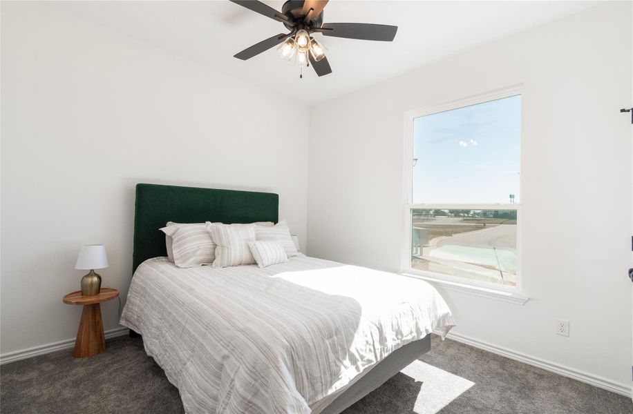 Bedroom with dark carpet and a ceiling fan
